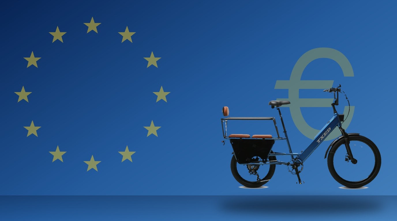 Blue TXED cargo e-bike in front of a European Union flag inspired blue background with gold stars and a euro symbol