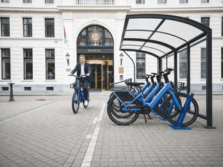 Branded electric bike docking shelter at a hotel entrance with shared electric bikes ready for guests
